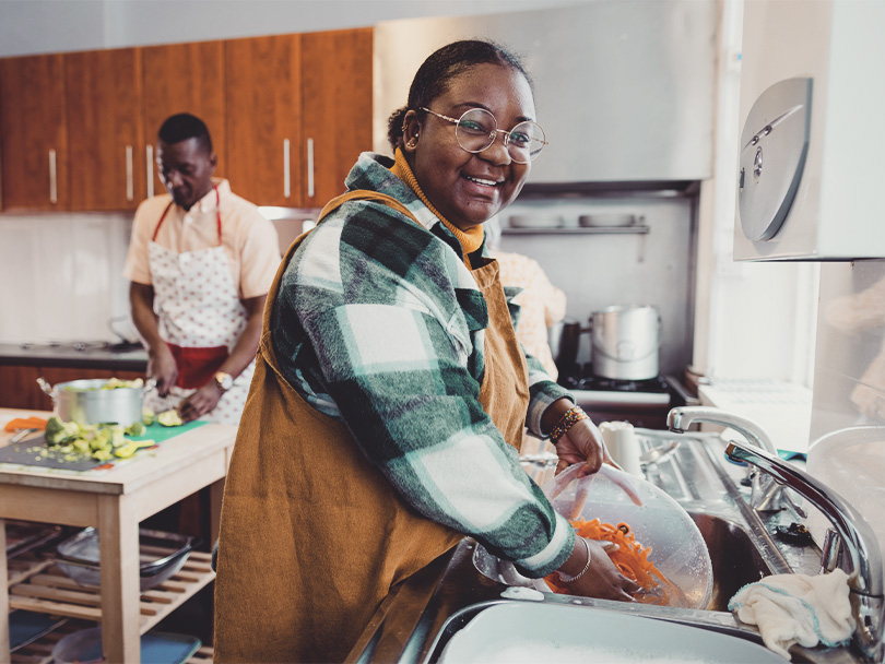 A shot of volunteers cleaning and washing up in the kitchen at a warm hub/food bank 