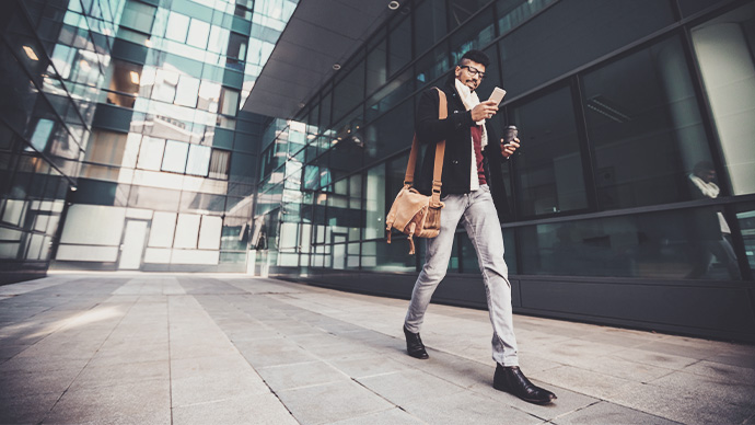 Young black business man using smart phone and drinking coffee to go