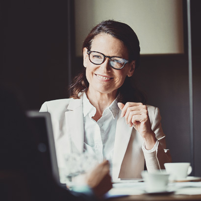 Happy businesswoman looking at colleague during meeting in hotel room